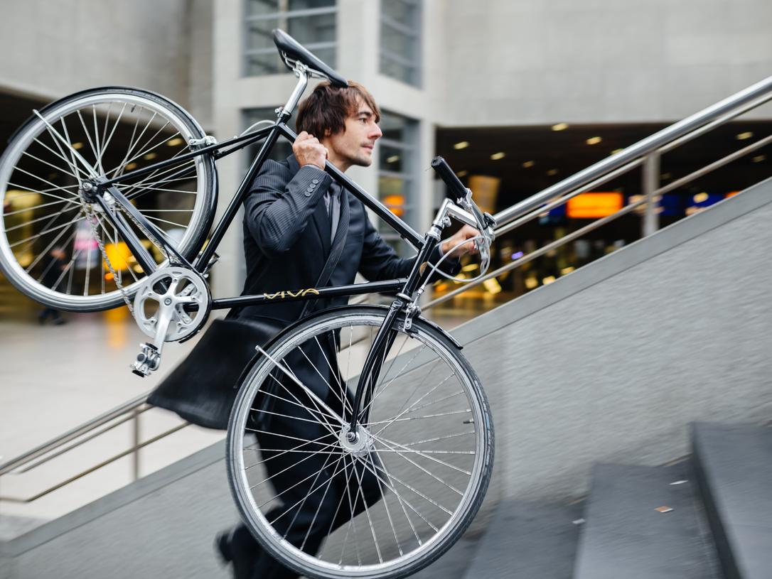 man in business suit carrying bike
