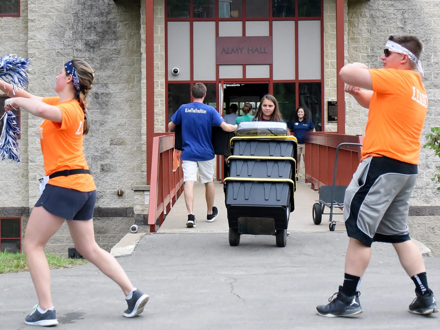 Two students dance outside Penn State Behrend's Almy Hall during move-in day.