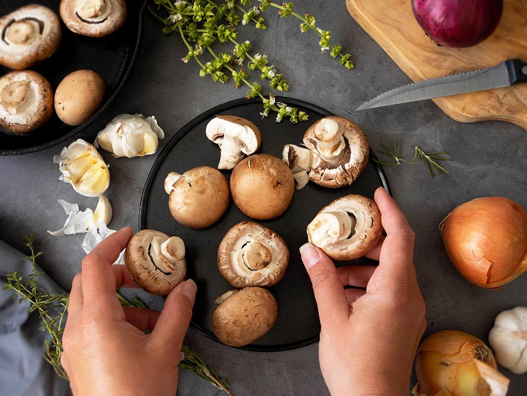 Two hands hold mushrooms that are ready to be prepared as part of a meal.