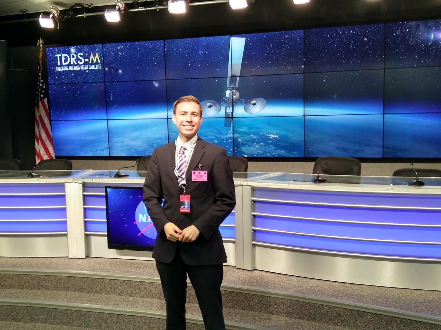 Drew Anderson in front of desk at NASA briefing room