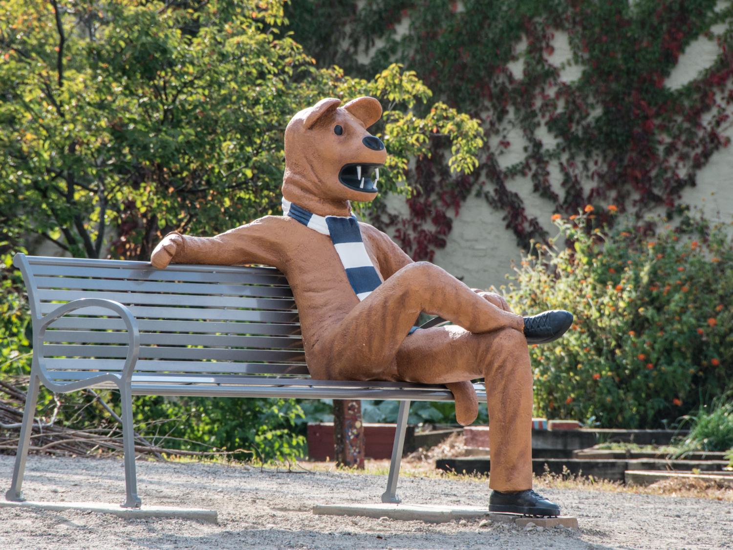 A life-size replica of the Nittany Lion mascot sitting on park bench.