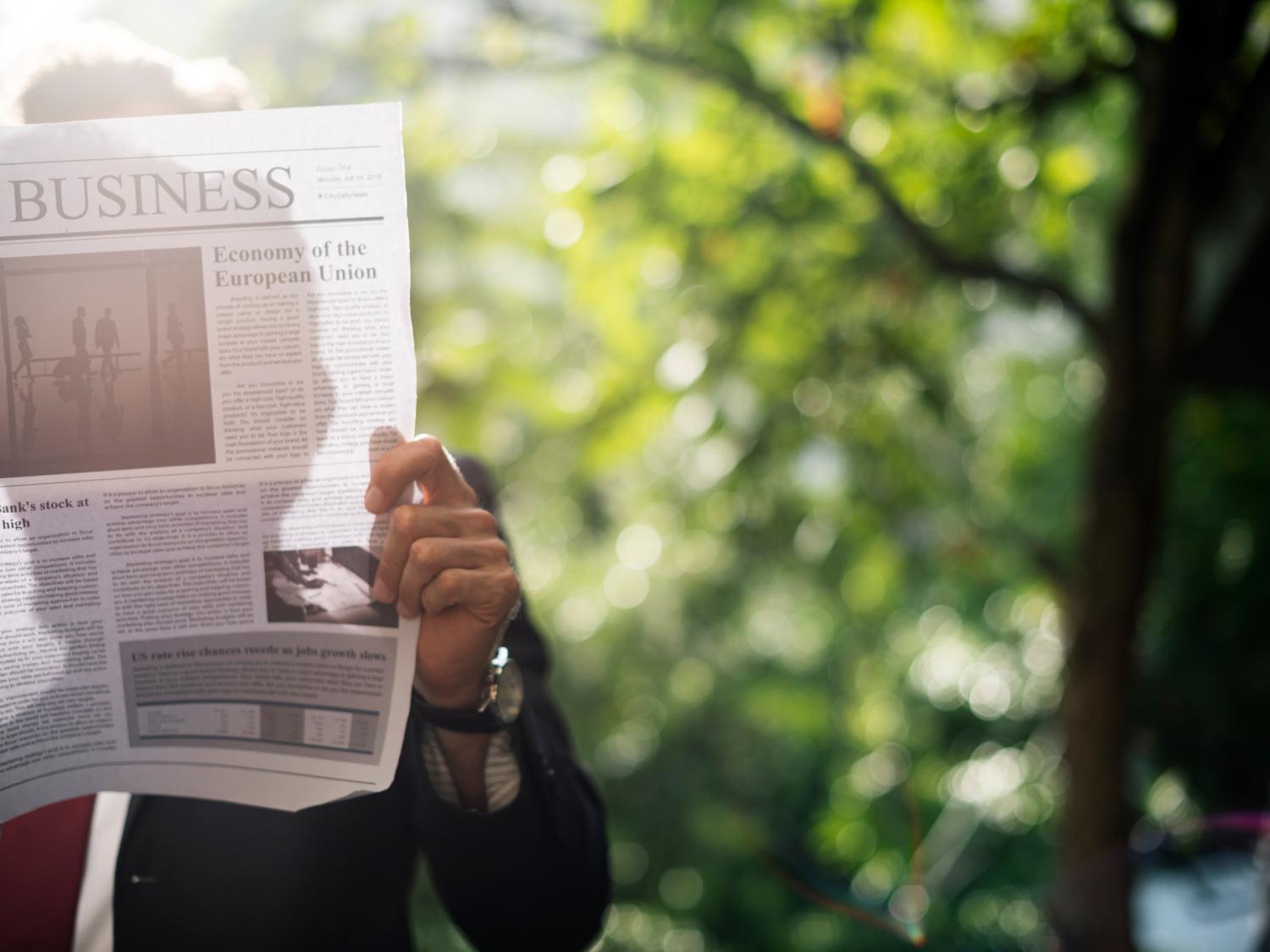 Man reading a newspaper outdoors