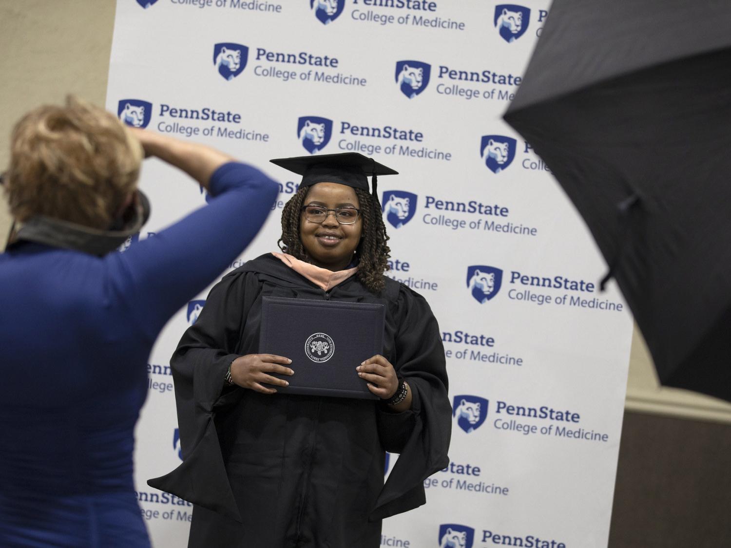 A student in a cap and gown poses for her official portrait.