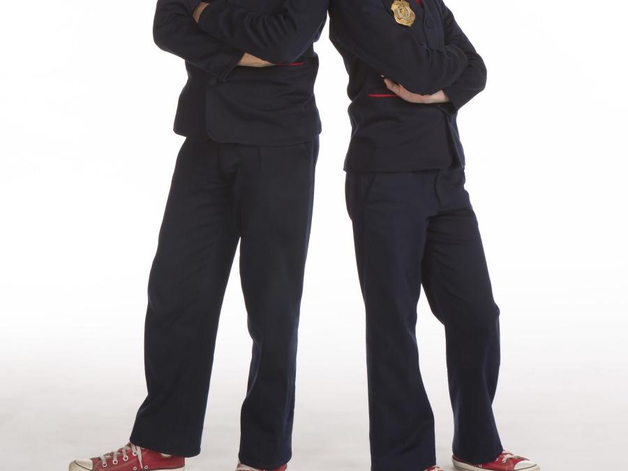 The agents of “Odd Squad Live!”—shown from their necks down—sport matching sneakers and suits emblazoned with an Odd Squad badge.