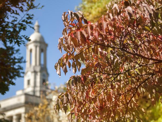 Old Main bell tower with autumn leaves in foreground