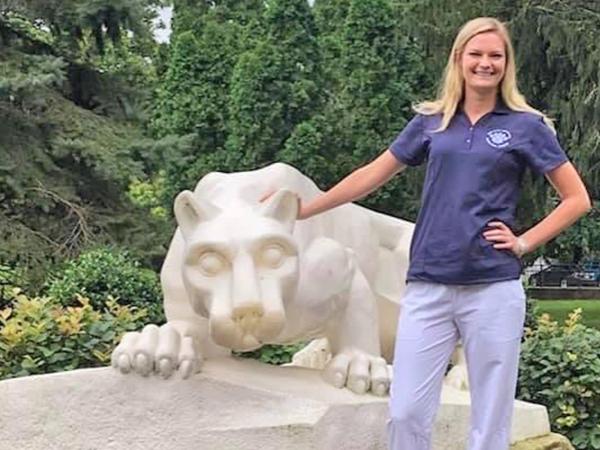 Student in blue scrubs at Penn State Schuylkill's lion shrine.
