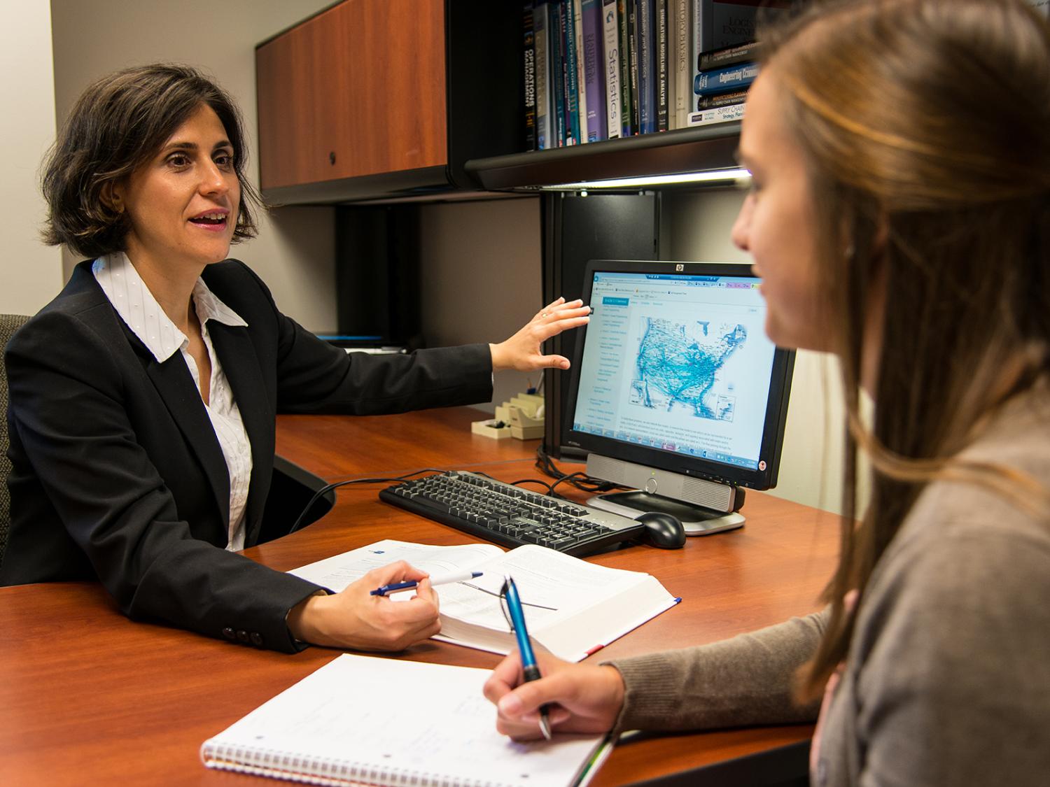 A professor at the Black School of Business discusses course material with a student.