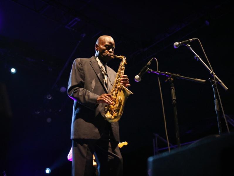 A man closes his eyes while he plays his saxphone on stage.