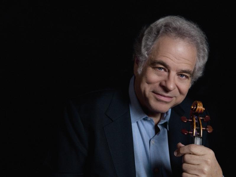 A man smiles as he holds his violin by the neck.
