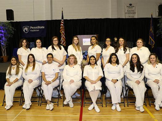 Group of 16 female graduates, seated and standing. 