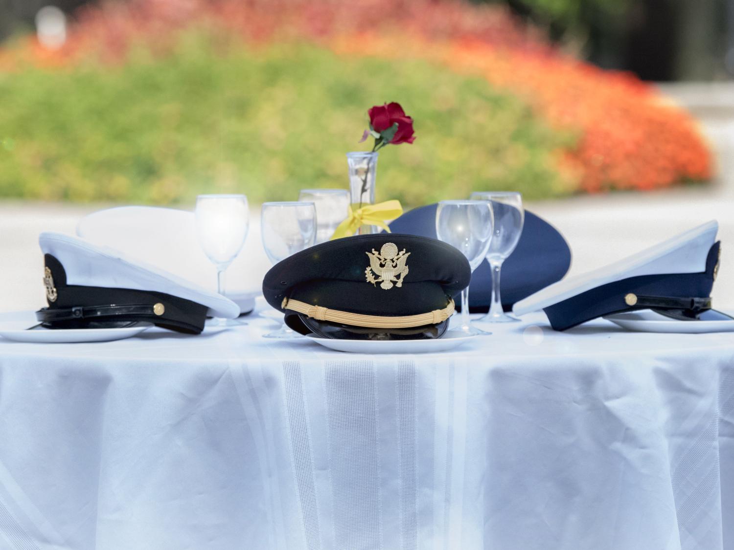 Hats from every military branch around an empty missing man table