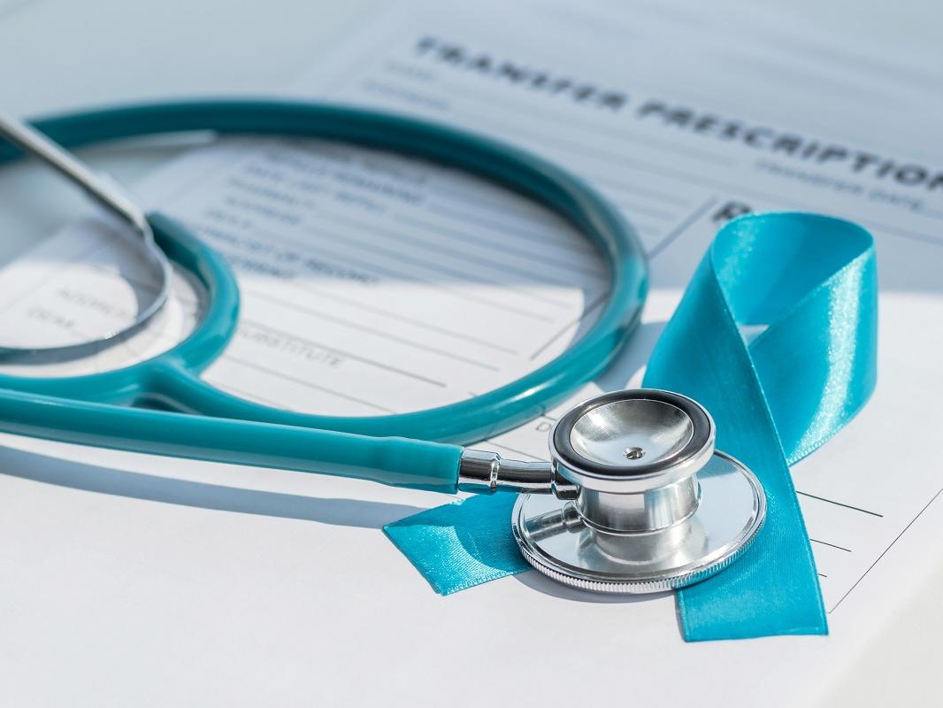 Blue ribbon symbolic of prostate cancer awareness campaign and men's health on patients health record prescription form with a stethoscope.