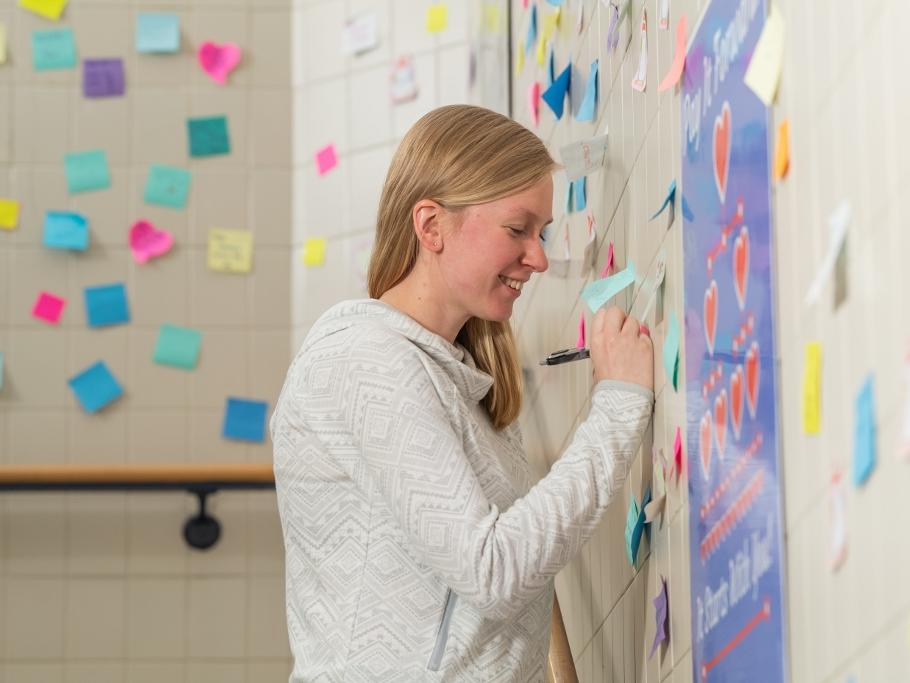 Penn State Behrend alumna Ashlyn Kelly writes on a sticky note in a stairwell of the Reed Union Building at Penn State Behrend.