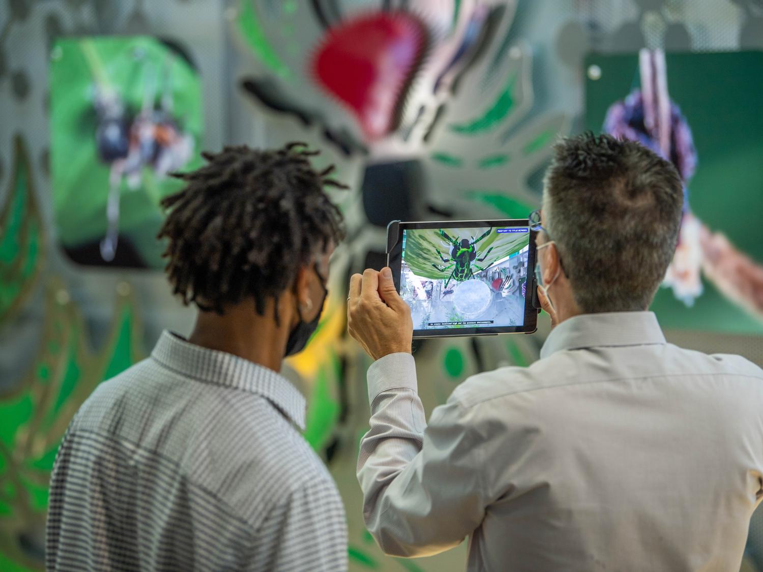 Two men use an iPad to explore the augmented reality element of an interactive art exhibit.