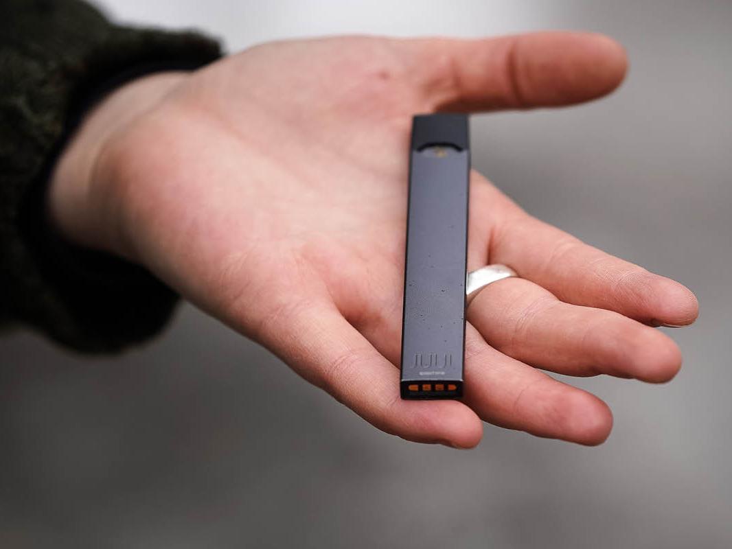 A person holds a JUUL electronic cigarette