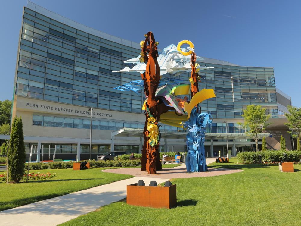 An external view of Penn State Children's Hospital. A multi-colored metal sculpture is in the foreground.