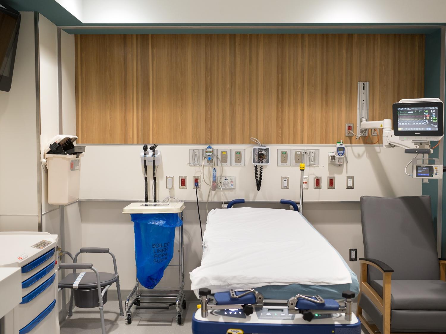 A hospital room with equipment including a bed, monitor screen, and various medical supplies.