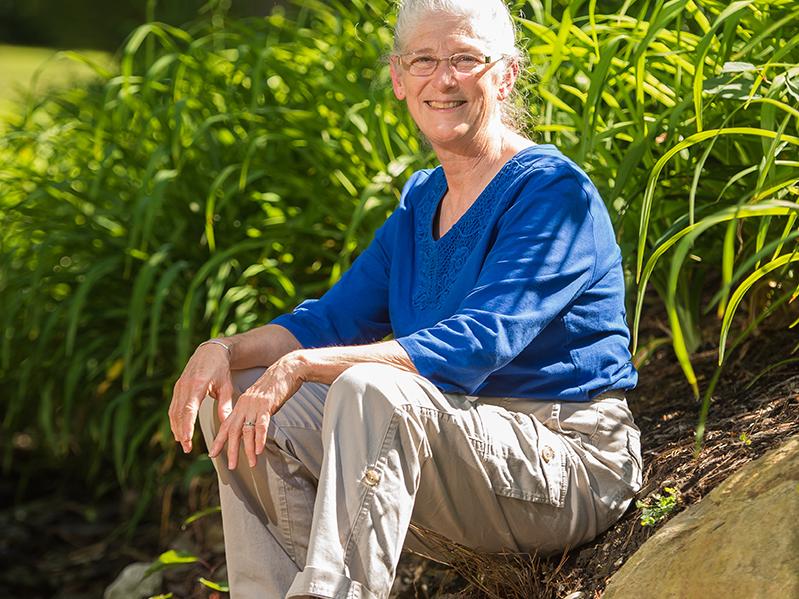 Pam Silver, interim dean for academic affairs at Penn State Behrend, sits next to a stream on campus.