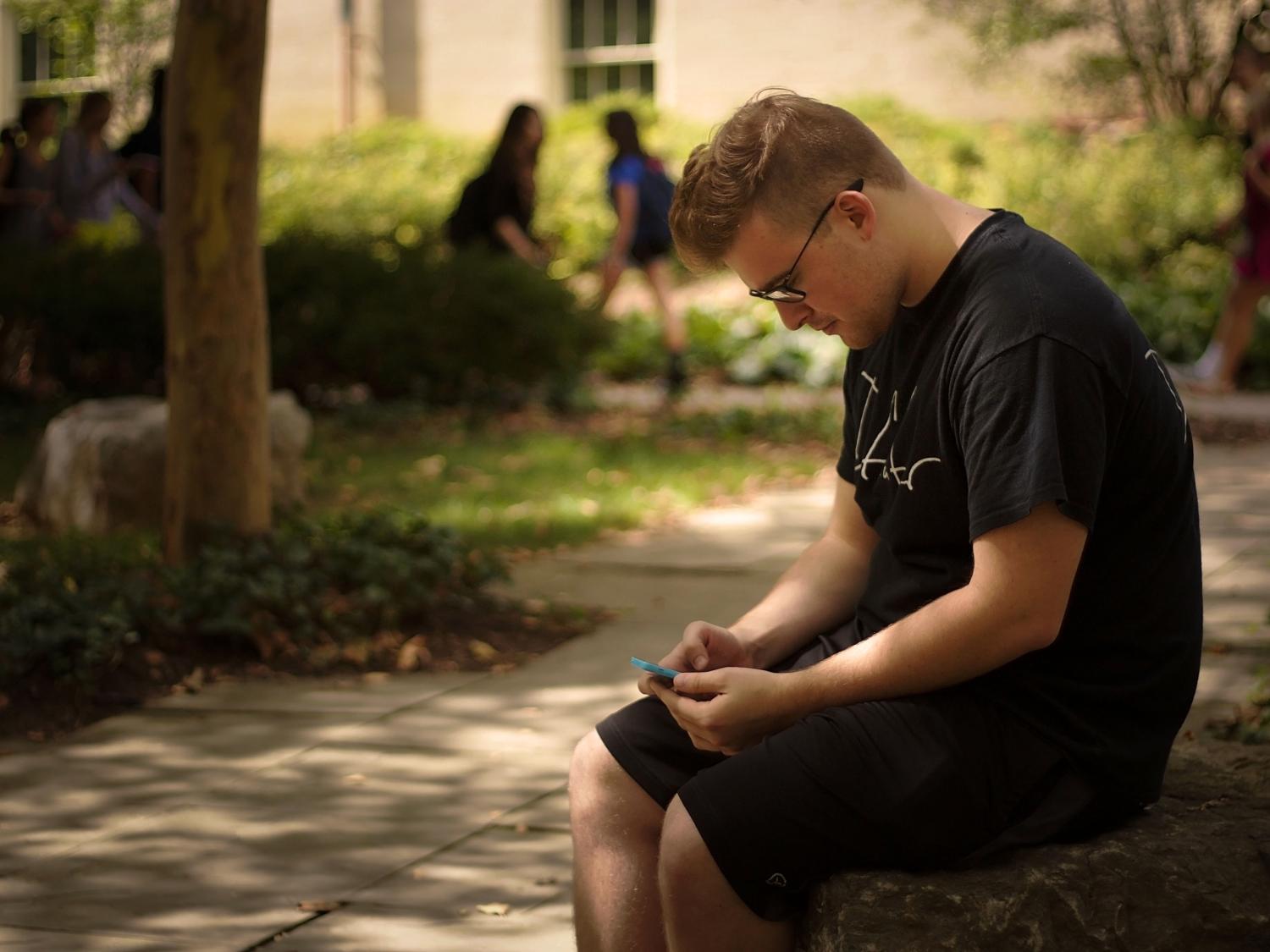 Patrick Dix sitting outside while checking his phone 