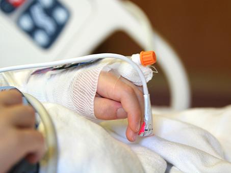 The hand of a child who's in a hospital bed.