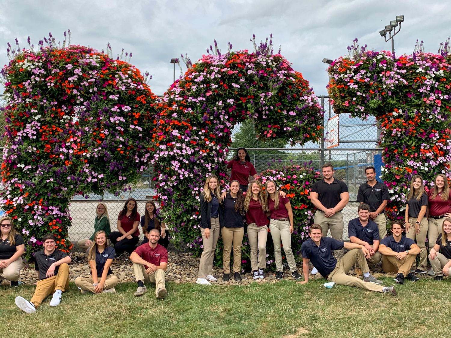 A group of students pose outside on a grassy lawn for a photograph.
