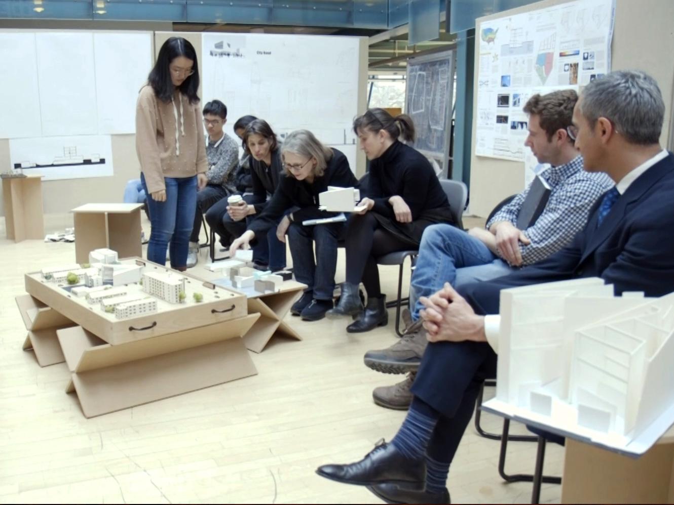 Ute Poerschke, center, points at a students' model during an architecture review.