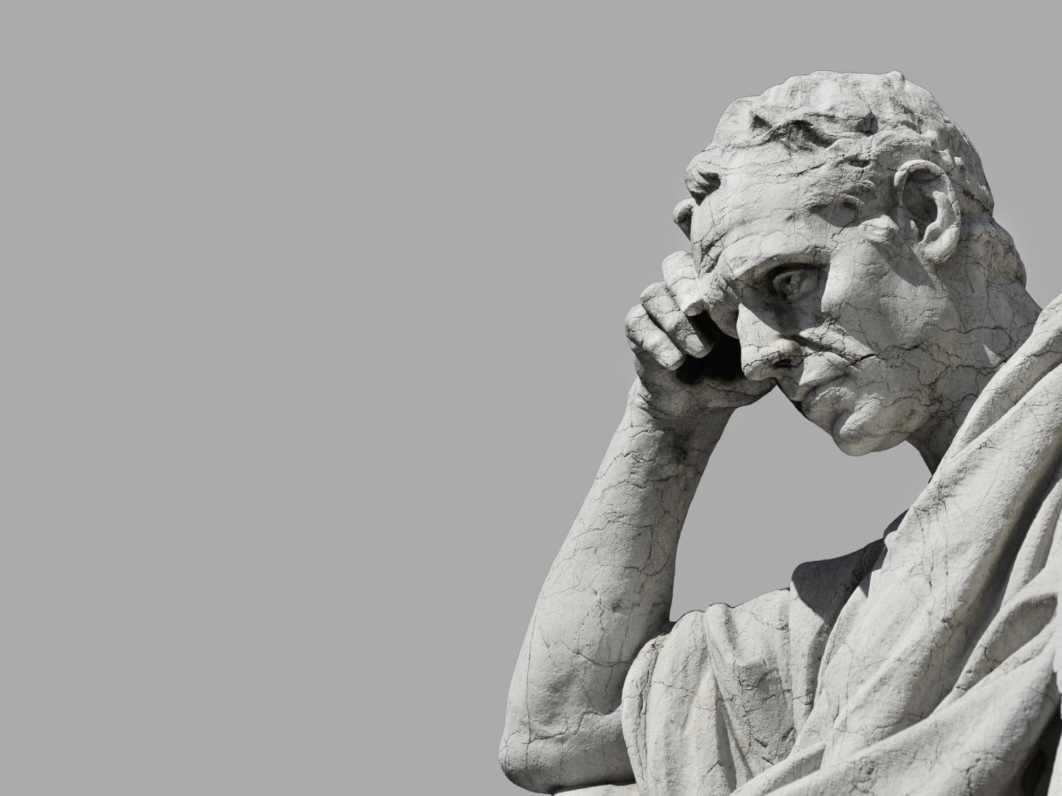 An image of a stone statue of a man thinking