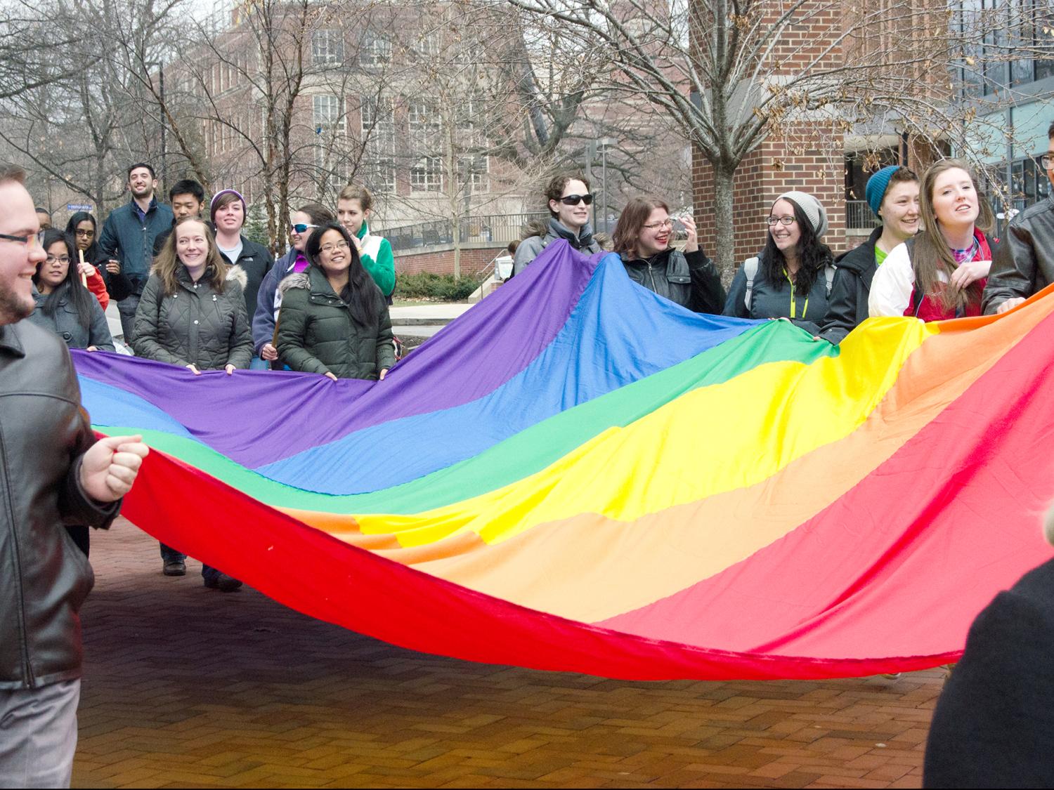 Pride Week Paraders walk with a rainbow flag