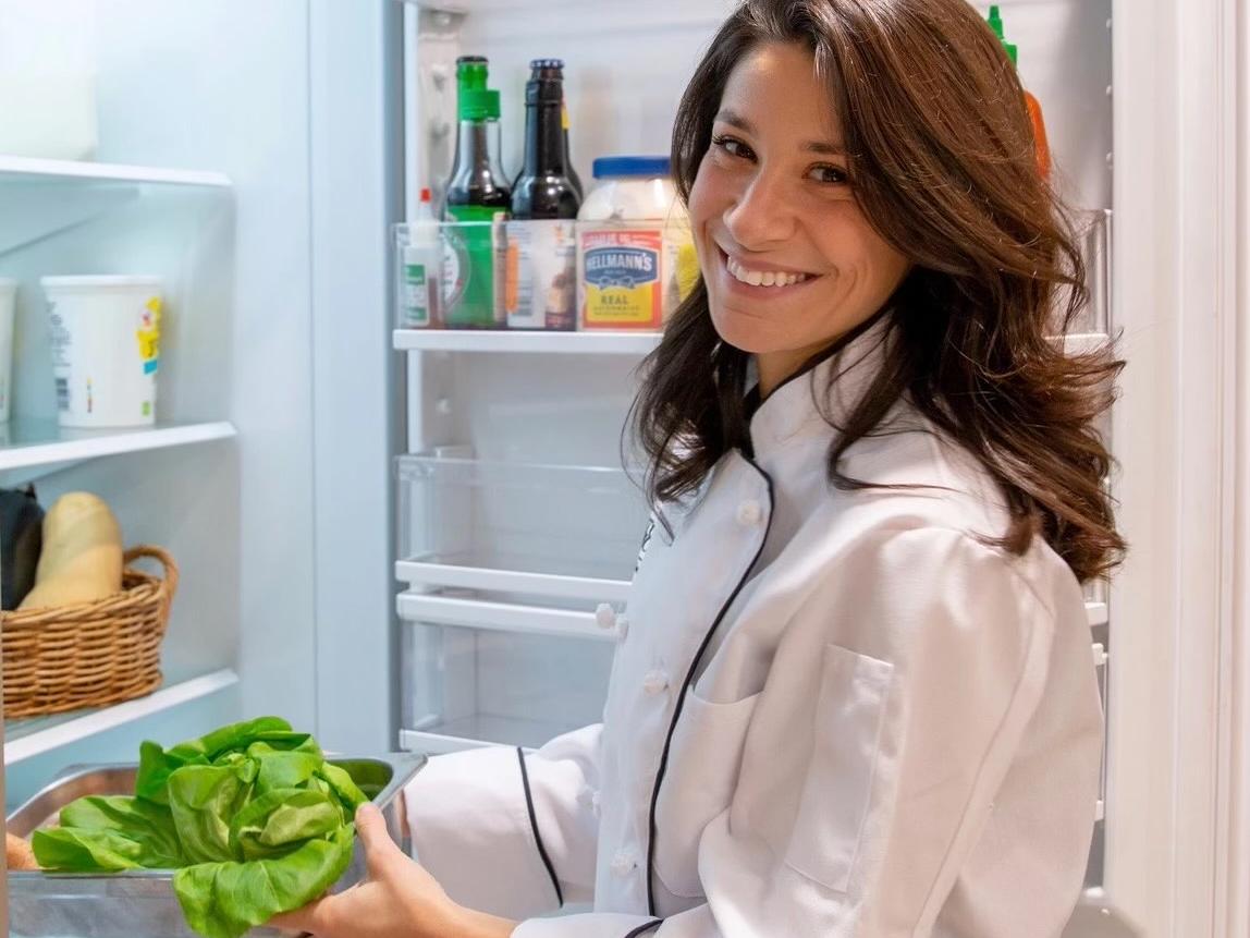 Olivia Weinstein holding fridge door open and holding bowl of lettuce