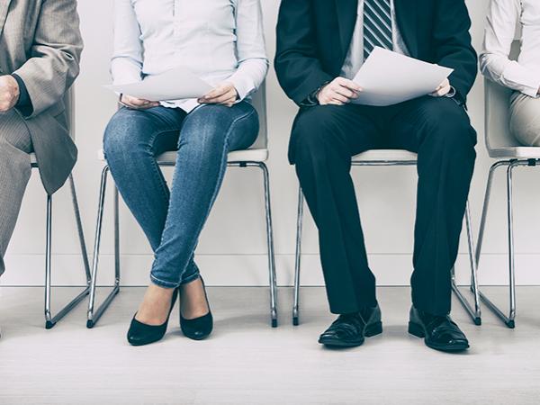 Photo of four men and women seated in a row and waiting for an interview