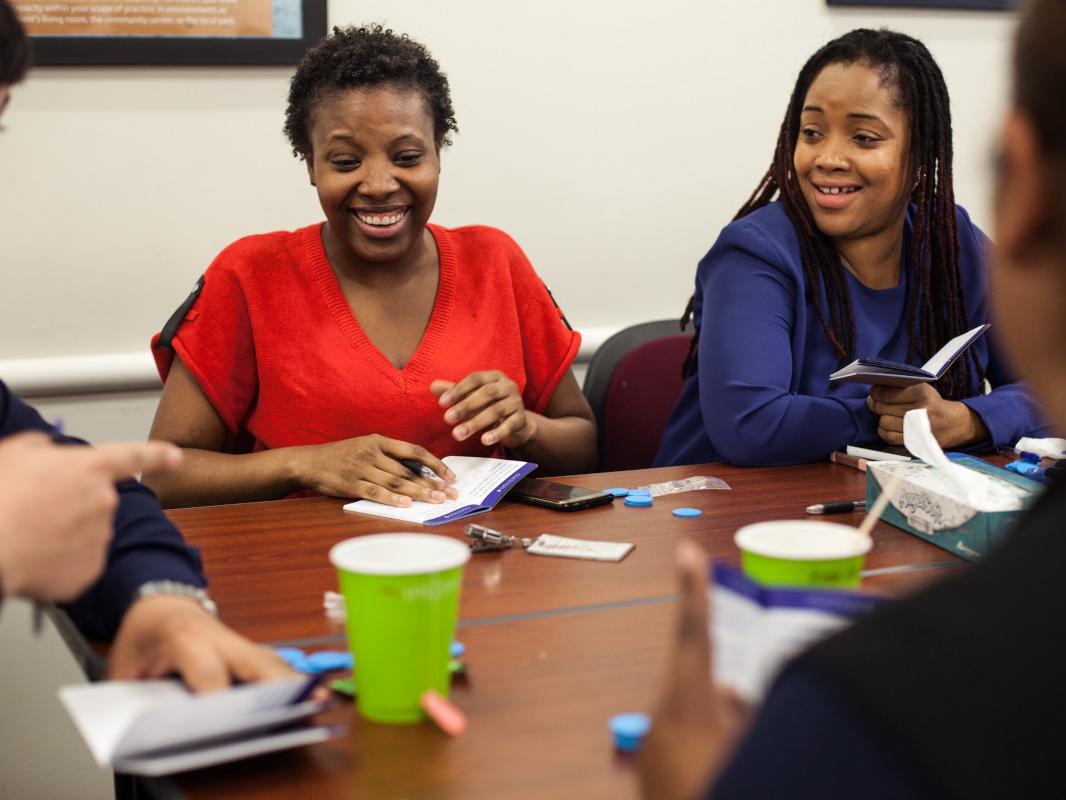 People sit around a table playing a board game