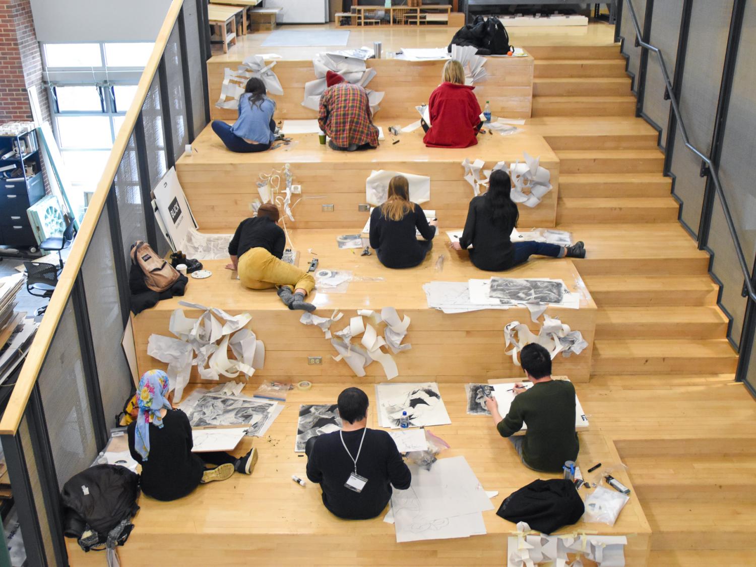 Students participating in a drawing workshop sit on the step of the mezzanine level of Stuckeman Family Building working on a workshop exercise.