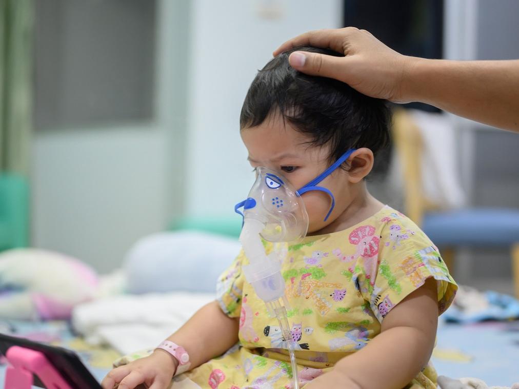 A baby with Respiratory Syncytial Virus in a hospital. She wears an inhaler containing medicine for stop coughing and disease flu.