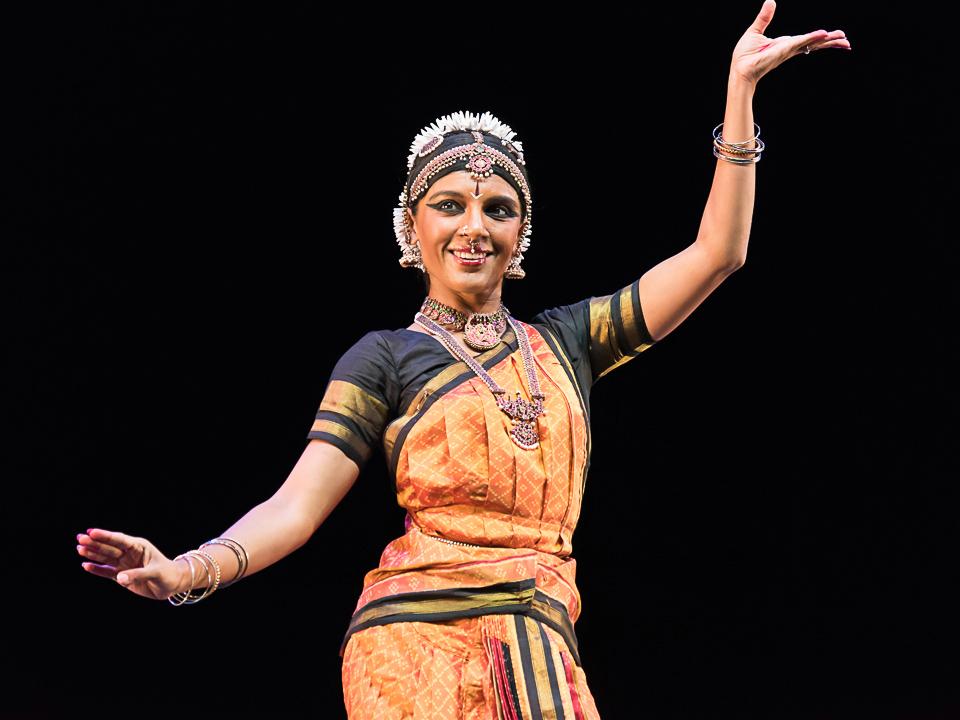 Ragamala Dance Company co-founder Aparna Ramaswamy, wearing an ethnic costume of intricate design, curves her hands during an Indian classical dance performance.