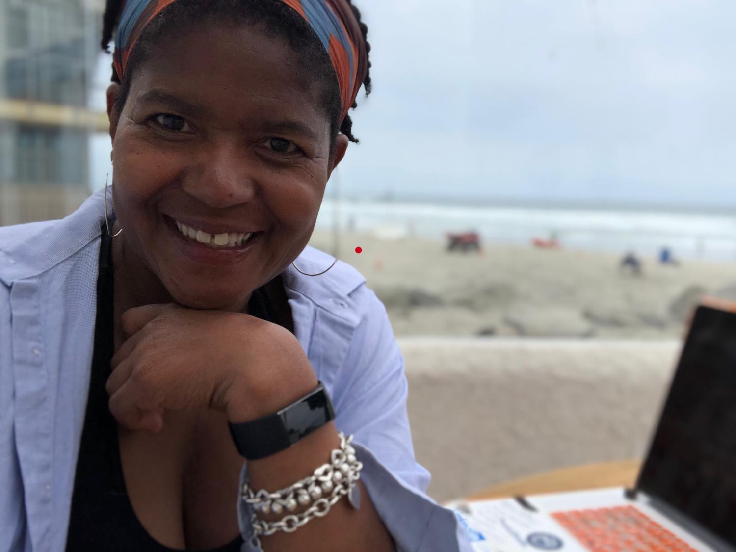 Renea Nichols sits by her computer on the beach.