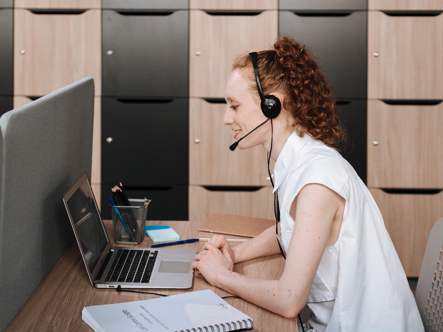 Woman wearing a headset and looking at a laptop
