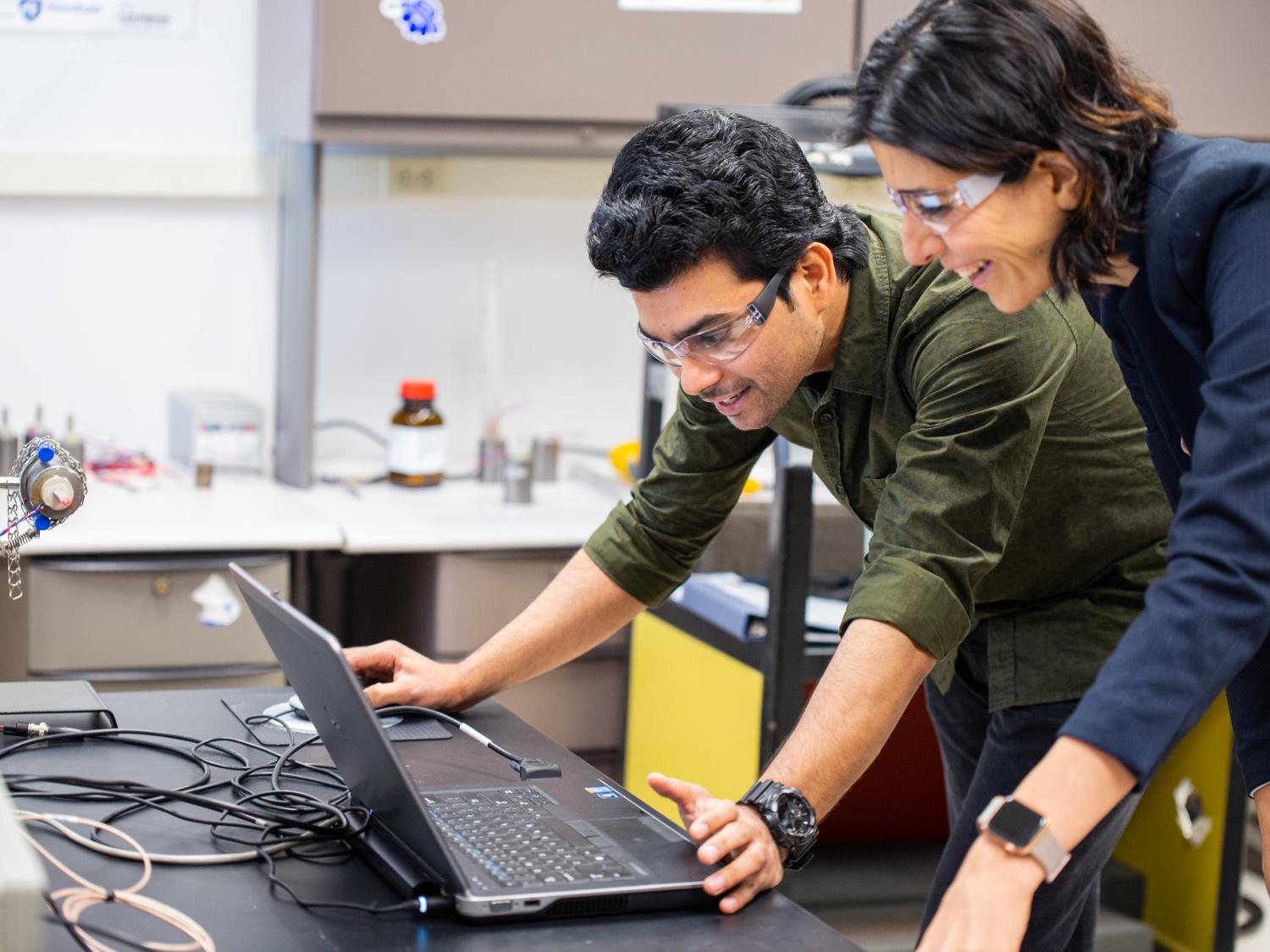 Man and woman look at a computer with smiles on their faces.