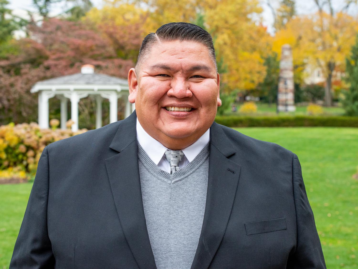 Man standing on the lawn outside of Hintz Family Alumni Center