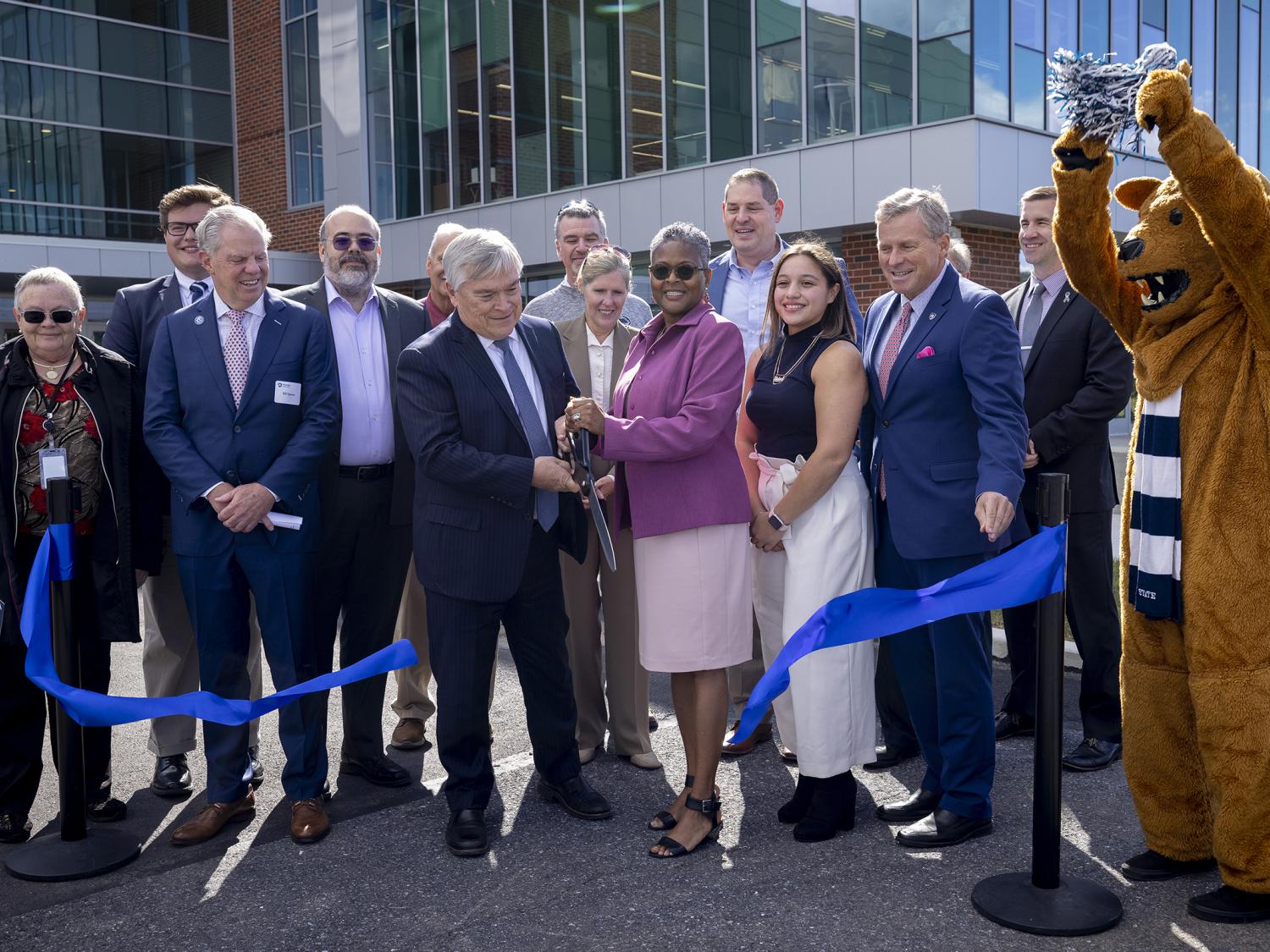 Penn State President Eric J. Barron and Penn State Lehigh Valley Chancellor Tina Q. Richardson cut a blue ribbon while standing in front of the new PSU-LV expansion.