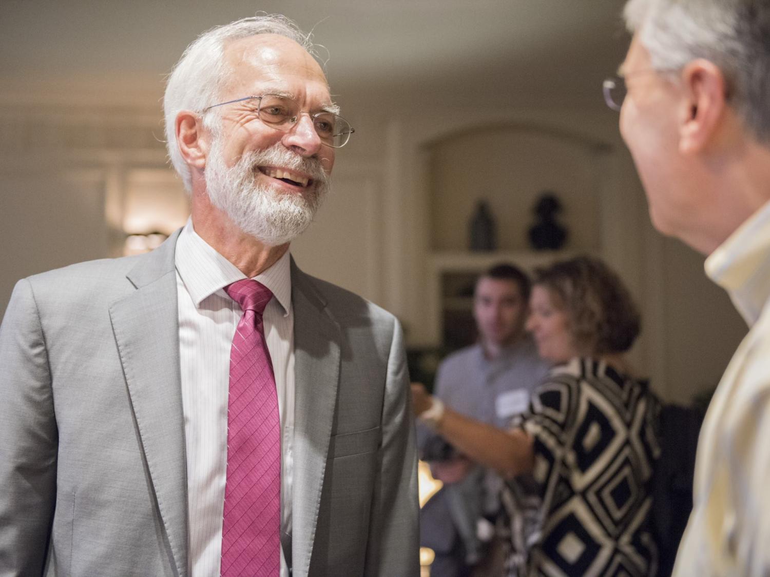 Rob Pangborn in gray suit and red tie speaks to another gentleman.
