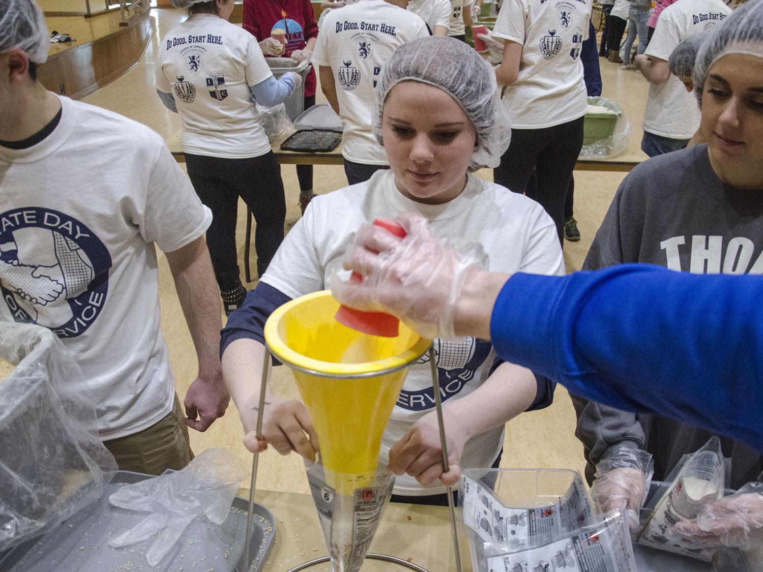 Students use a funnel to fill a bag with dry foods