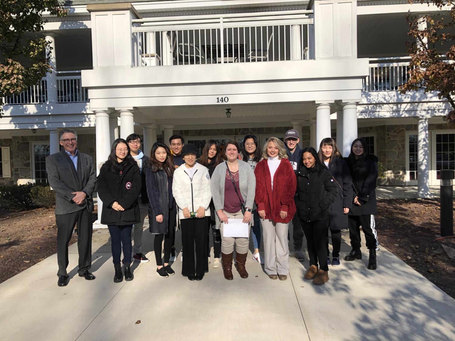 Students standing in front of a continuing care retirement community entrance