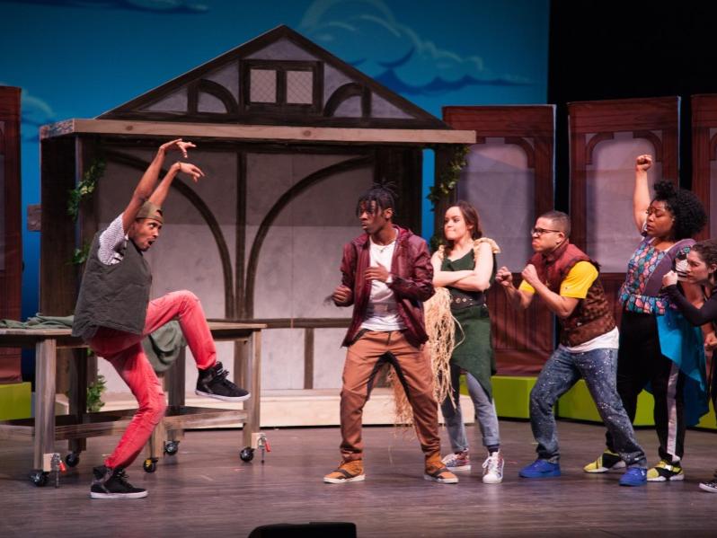 A man off to the left stands in a karate-kick pose while a group of people off to the right watch him with caution.