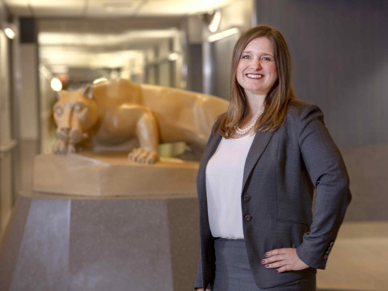 Deborah Berini poses in professional attire with the Nittany Lion statue to her side, in the background.