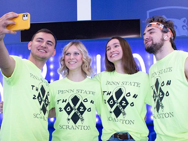 four students in bright yellow Scranton THON t-shirt pose for selfie