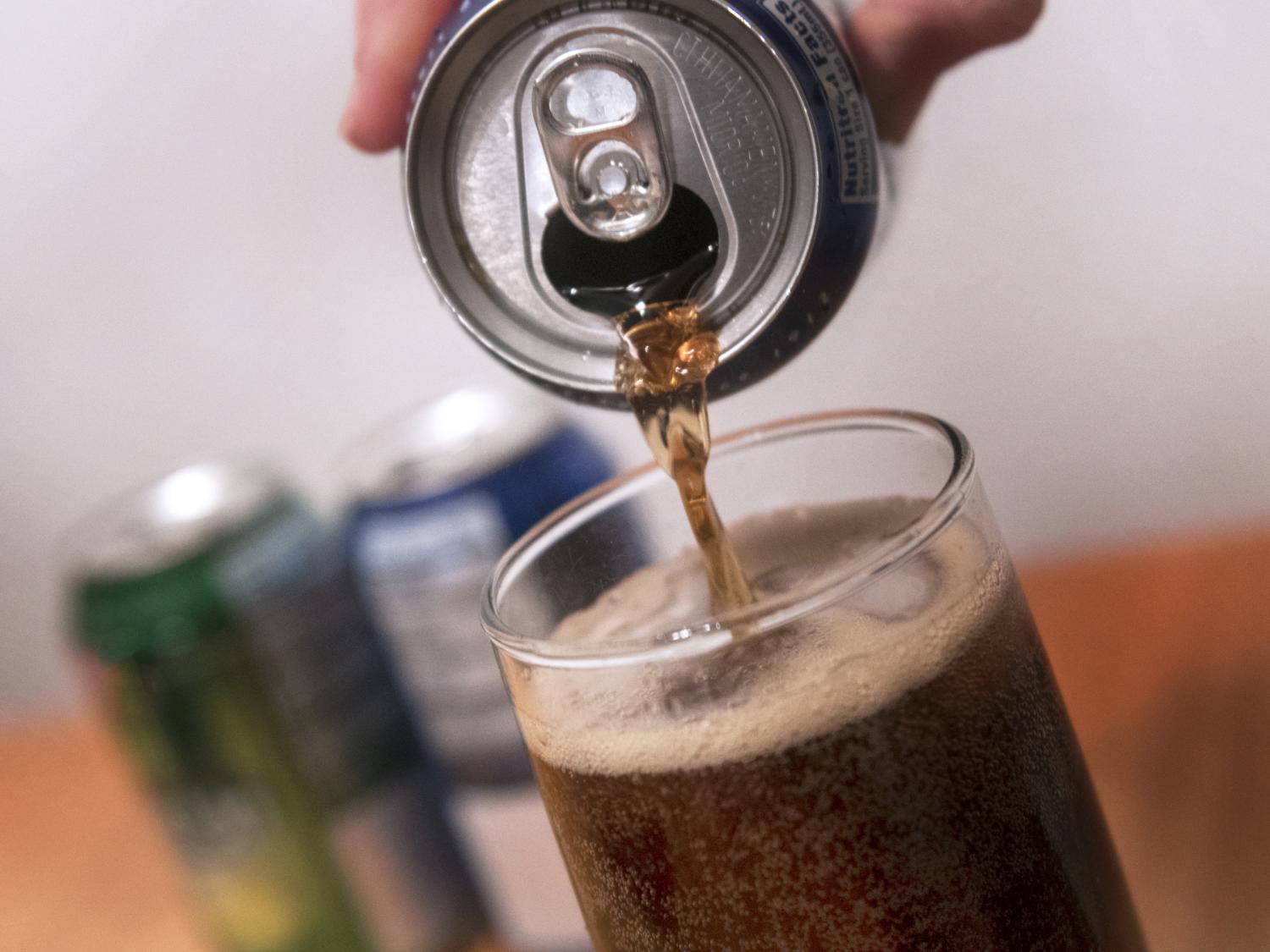 Close up of a can of soda being poured into a glass