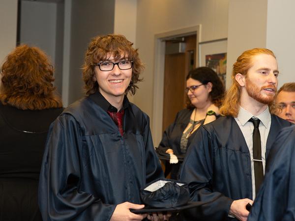 Penn State Beaver graduates wearing gowns talk after ceremony.