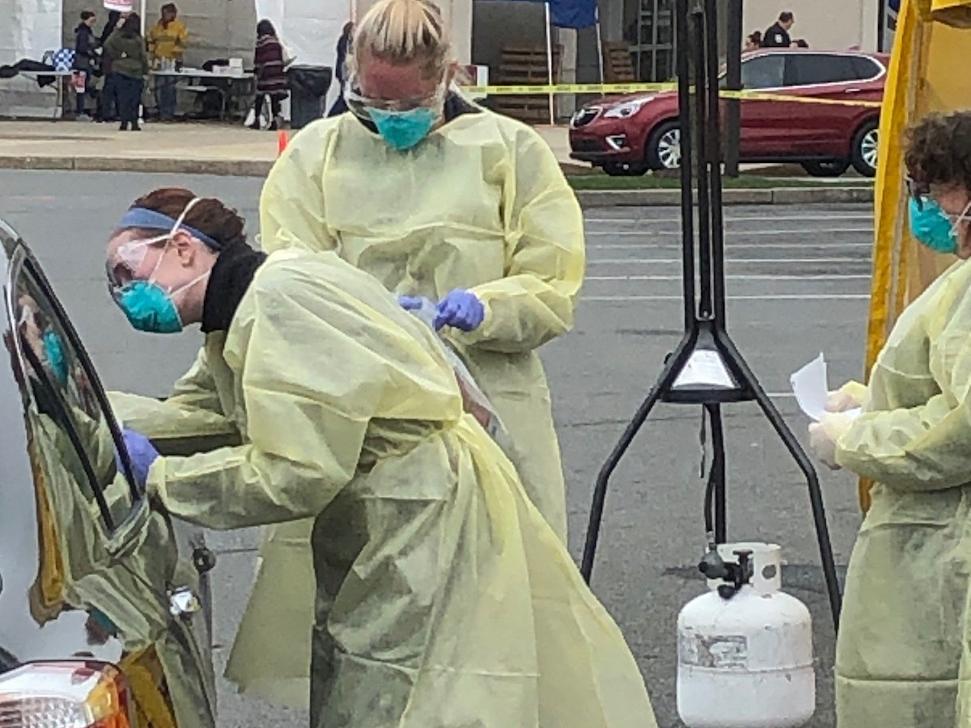 Nurses swab a patient in a vehicle at a drive-through testing site