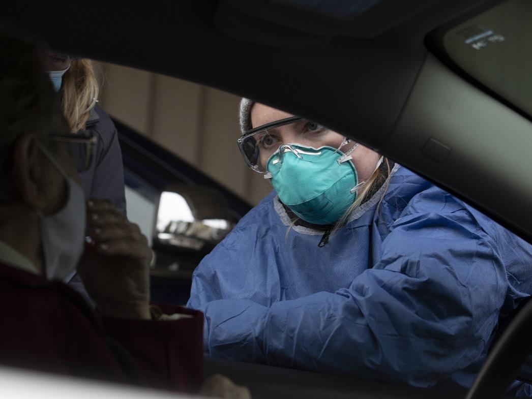 A nurse in a face mask gives instructions at a COVID-19 testing site