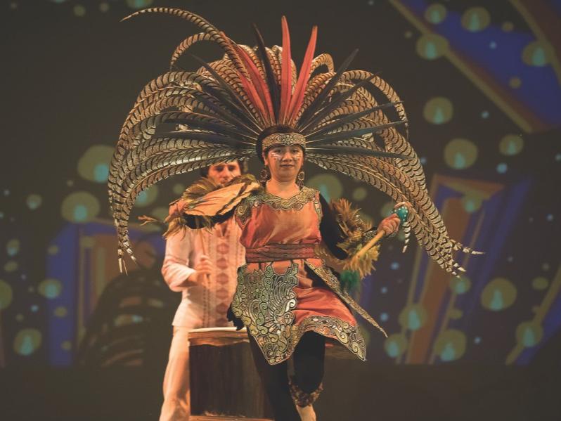 A woman wears a headdress adorned with long feathers.